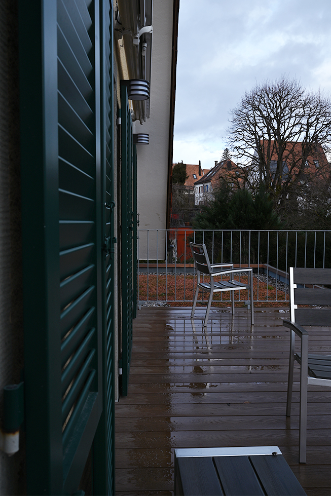 Terrasse, Regentag, Vorfrühling, Metallgartenstühle, Geländer, Gartenlampen, originale grüne Markisen